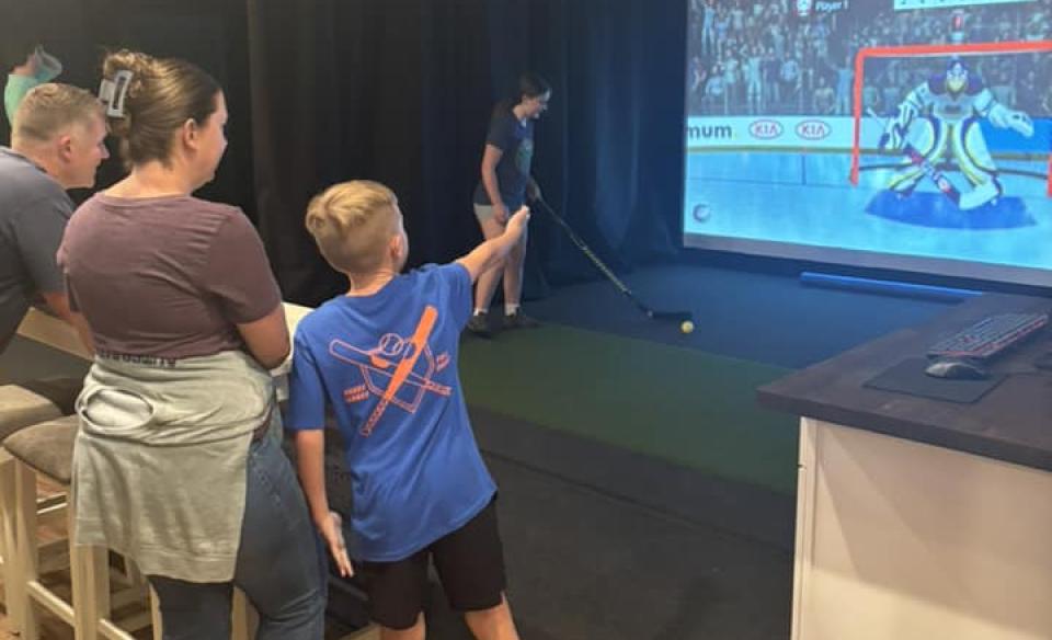 a family watching someone play virtual hockey