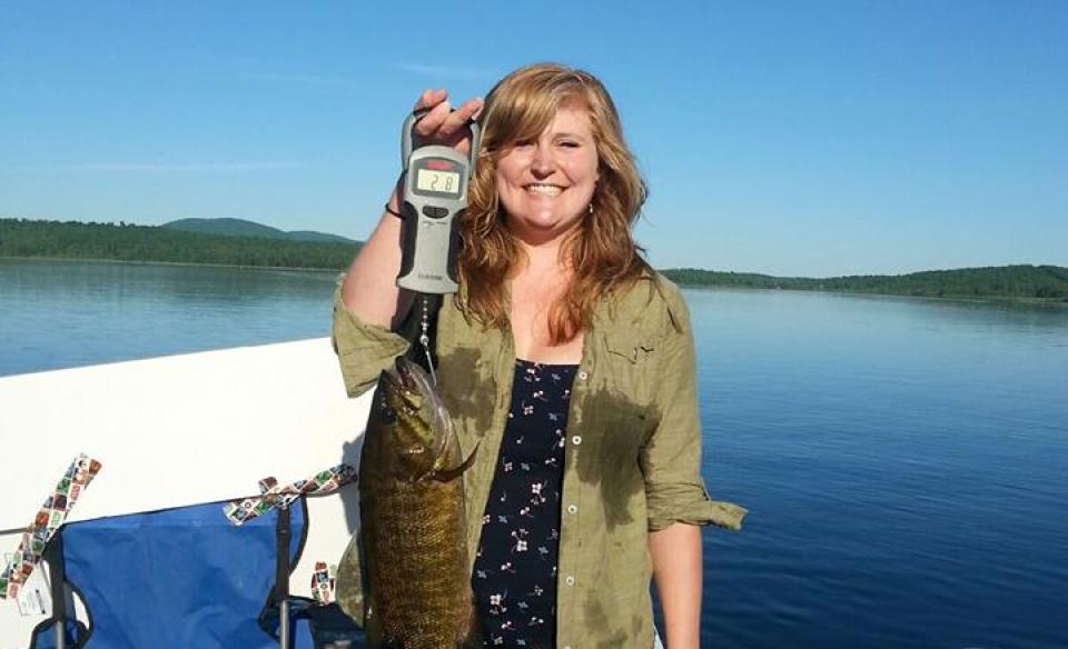Women holds up a hand held fish scale