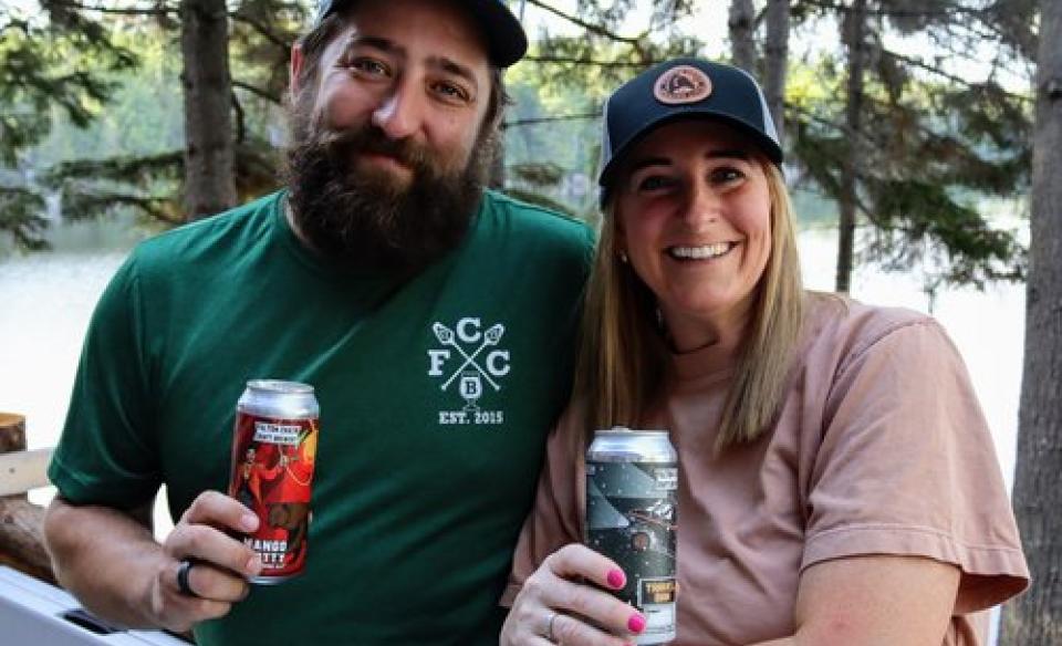 A couple posing for a photo holding a can of craft beer