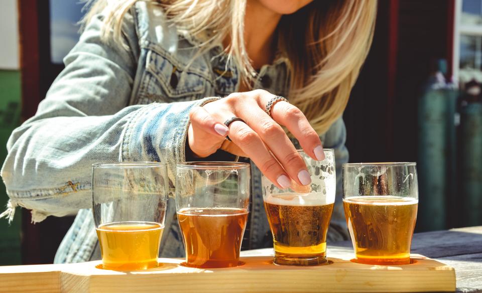 a woman tasting a flight of beers