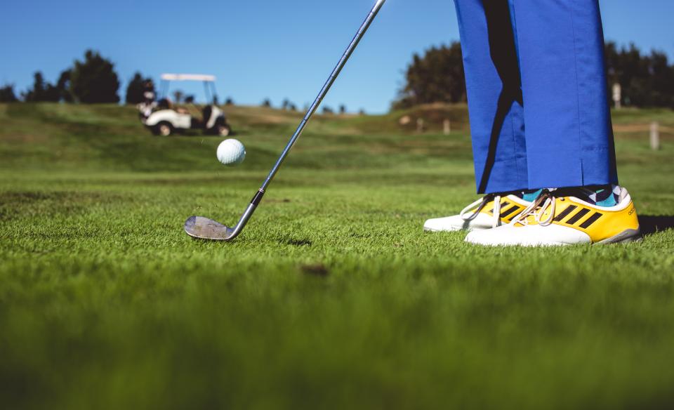 phot of a golfter wearing bright blue pants and yellow and white golf shoes