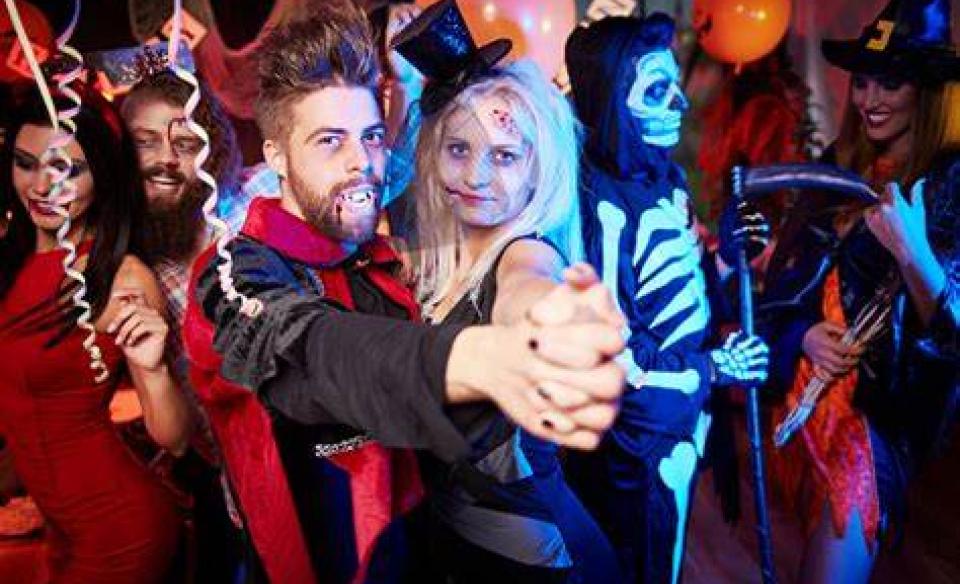 A photo of a man dressed as Dracula and a woman also dressed for halloween dancing at a party
