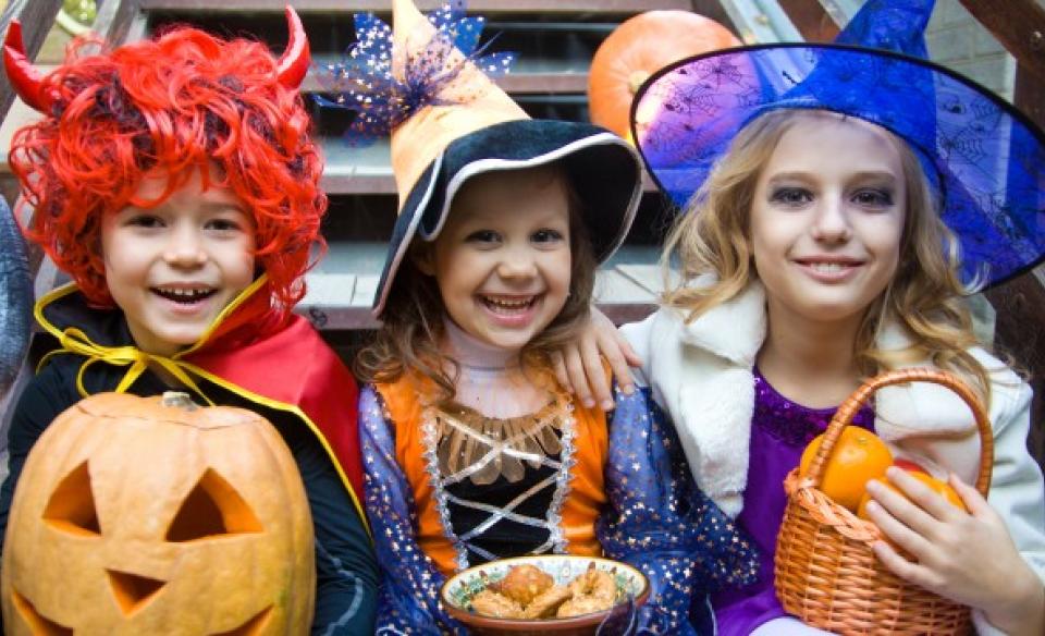 Three kids dressed up for halloween posing for a photo