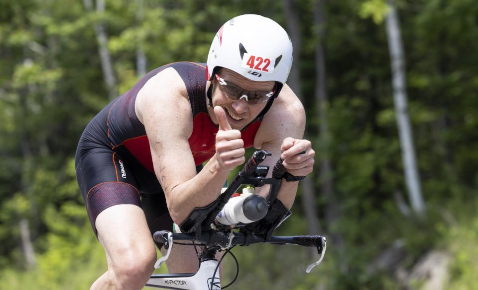 Tinman athlete give a thumbs up as they pass the camera on a bike.