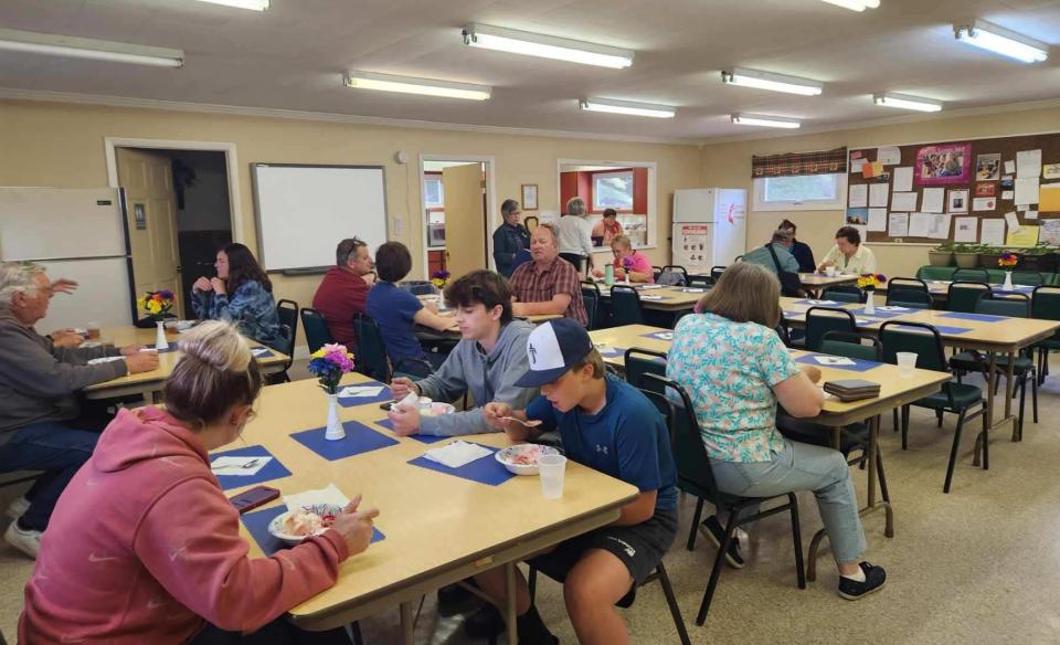A group of people are sitting at tables in a community hall