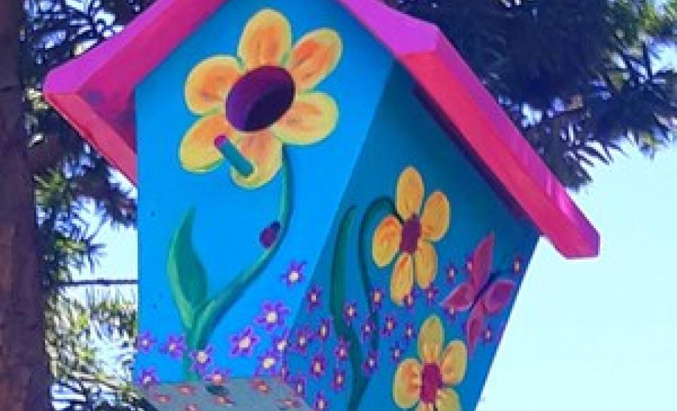 hand painted bird house hanging in tree.