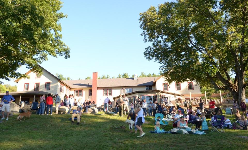 Large group of people gathered on a grassy lawn in front of a large