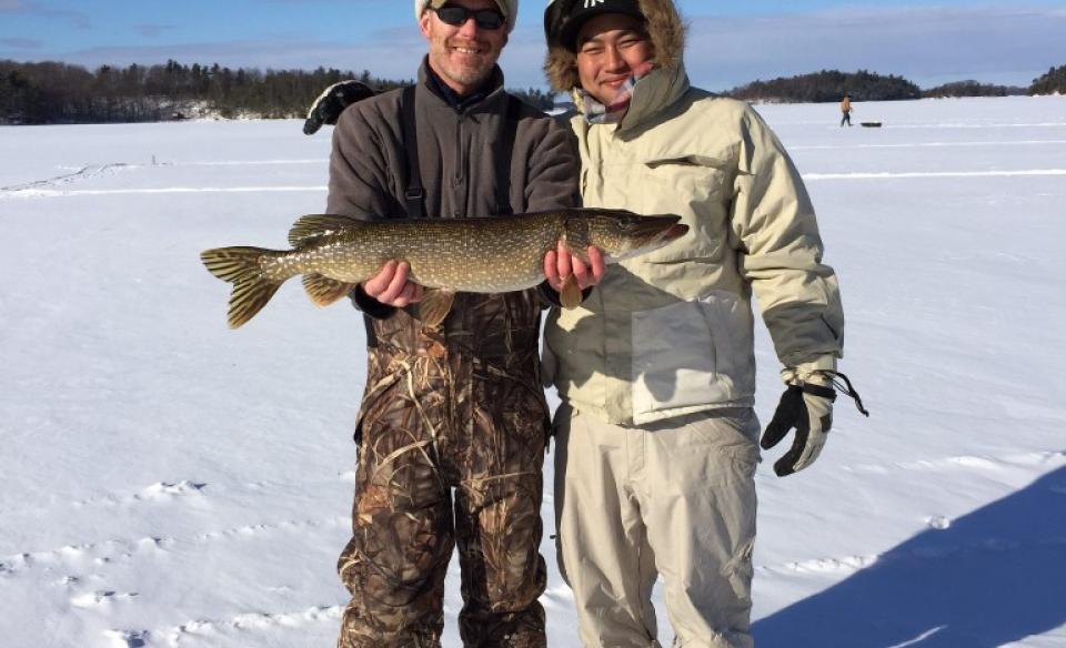 Two men holding large fish on the ice