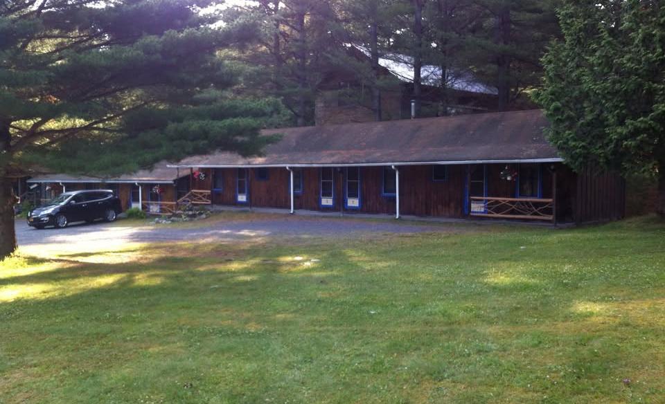 The large lawn and exterior of the brown building and white trim of the Blueberry Hill Motel