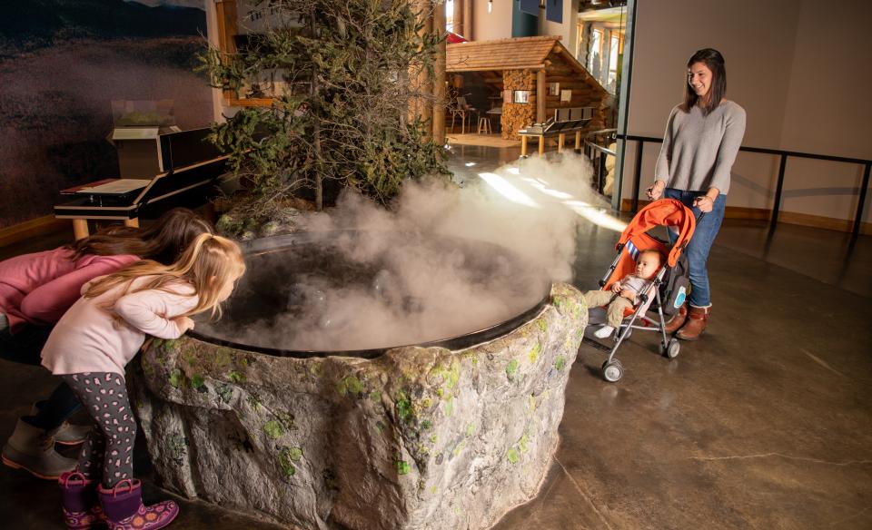 Two children play a game throwing snowballs into buckets set up on a suspended walkway on the Wild Center's Wild Walk
