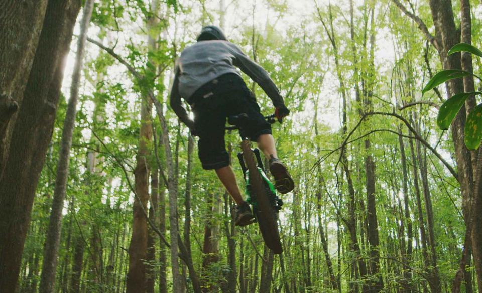 A mountain biker catches air amongst the trees