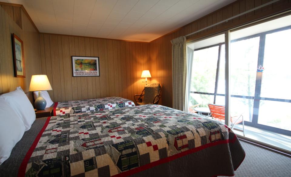 A two bed room looking out large windows on a balcony.