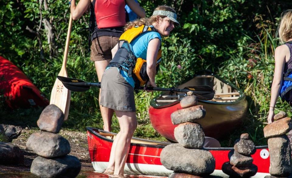A smiling woman in a life jacket ready to board a boat.