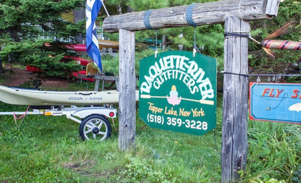 The green sign for Raquette River Outfitters