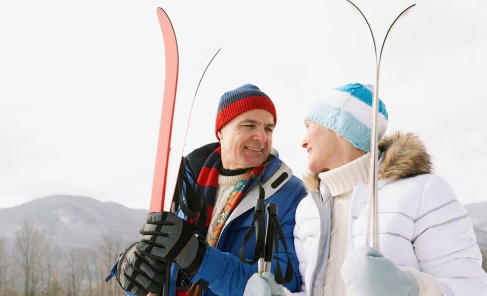 A smiling couple holding snow skis