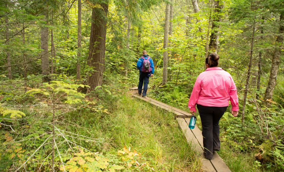 Two people walk on a board bridge on the OK Slip Falls trail.