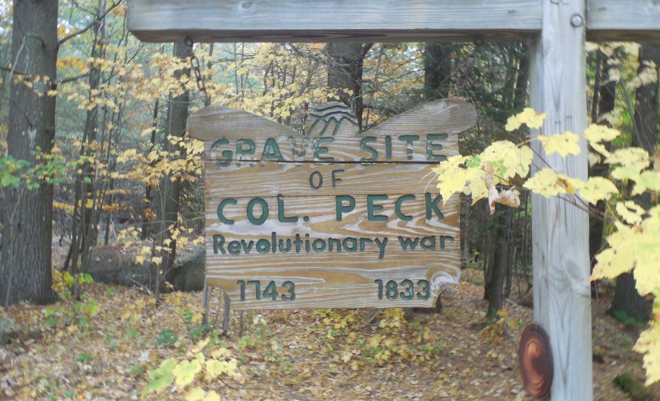 A wooden sign for Col. Peck's grave site