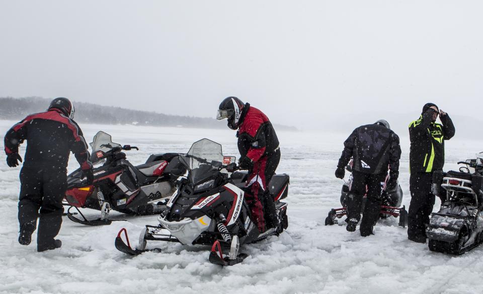A group of snowmobilers stopped on the trail