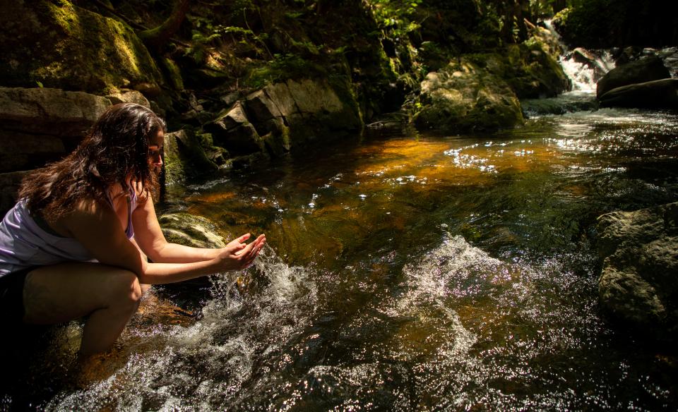 A woman sits and dips her feet in a pool downstream from East Jimmy Creek Falls