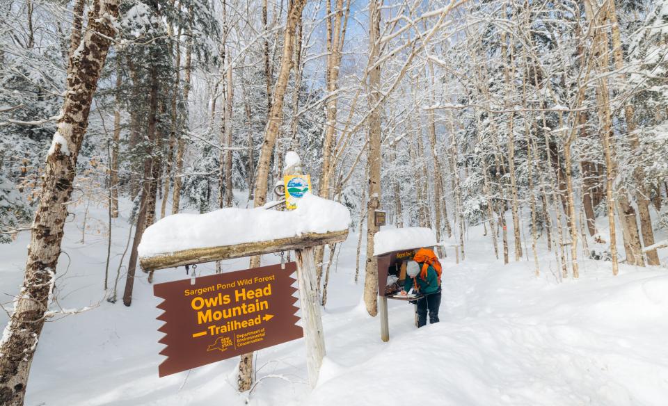 A winter hiker signing into a trail register