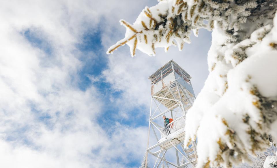A hiker on the snowy firetower on Owls Head Mountain