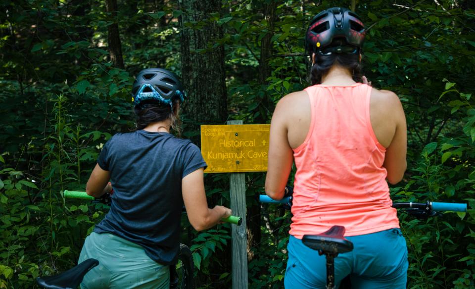 Two bikers looking at the sign for Kunjamuk Cave.
