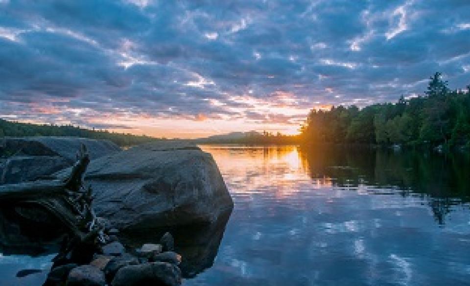 The sun setting at Forked Lake State Campground beneath a cloudy sky