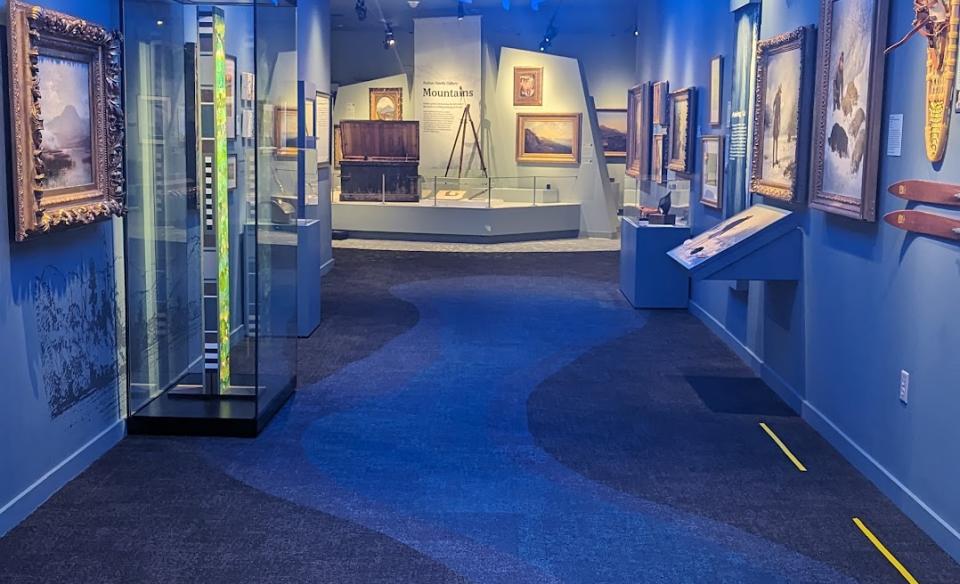 Art pieces on display in a long hallway with blue walls