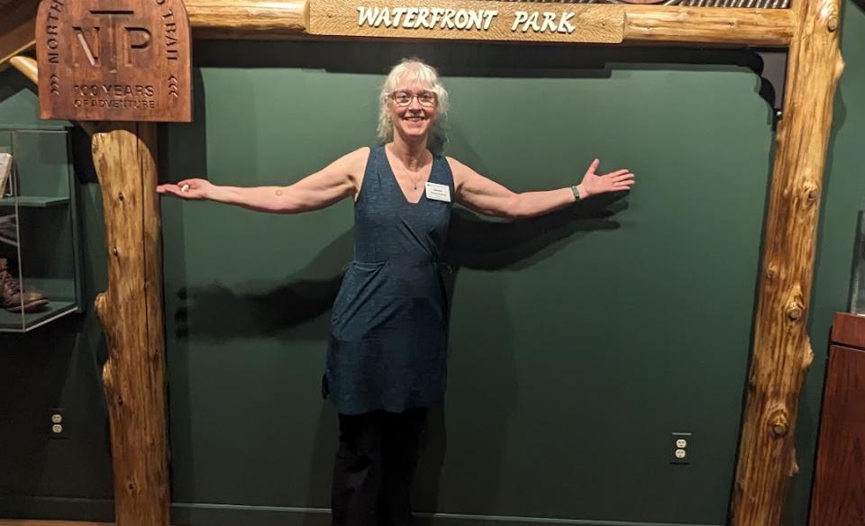 A woman smiles under a wooden arch against a green wall where plaques describing the NPT are displayed