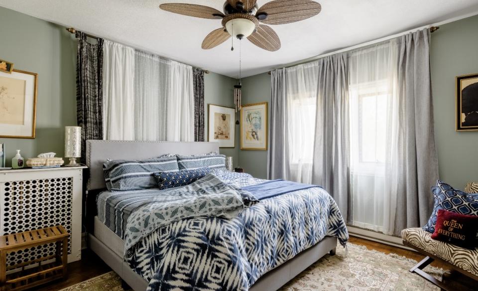 A guest bedroom with large bed floor to ceiling window treatments and light accents.