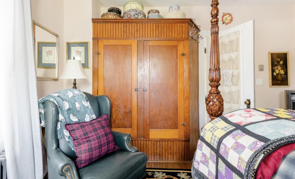 large wooden wardrobe with a leather wingback chair in a guest room
