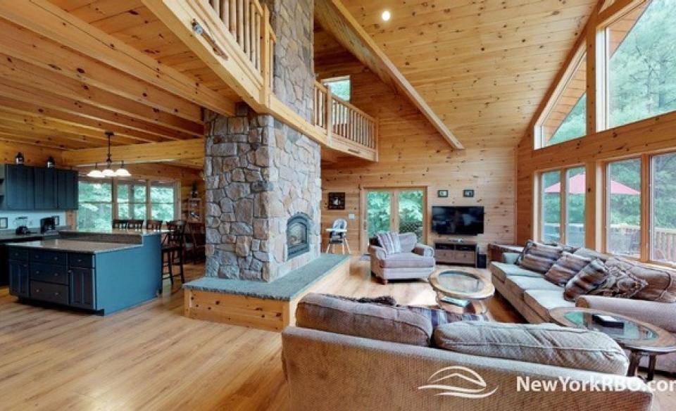 A spacious living room with central fireplace and large couches by the big windows.