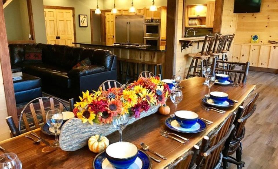 A large dining table set for 8 with sunflower centerpiece and happy blue flatware.