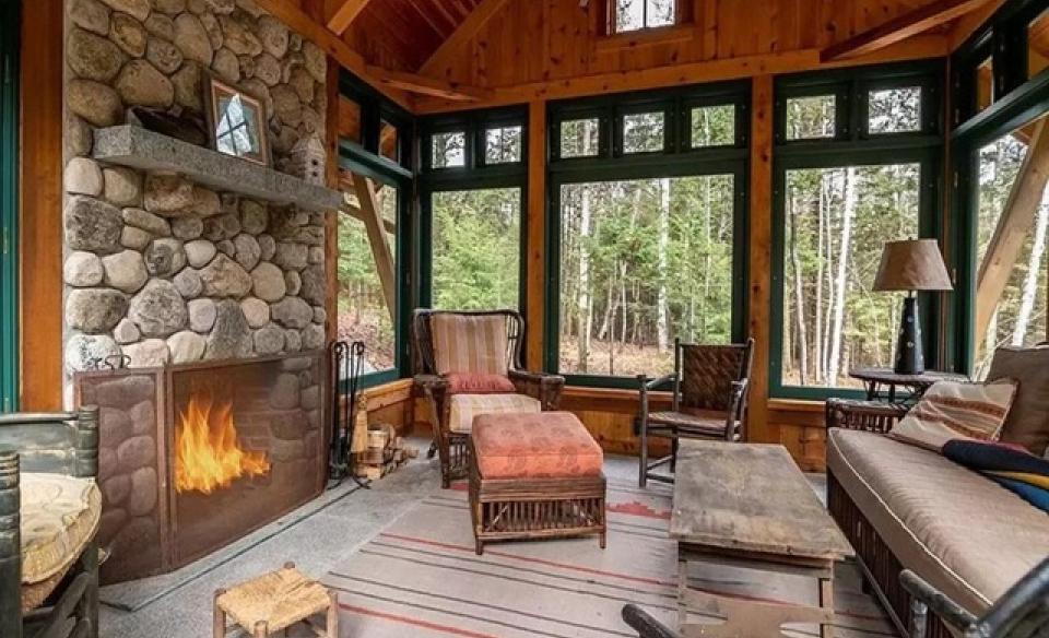 A three season room with tree views and a large stone fireplace.